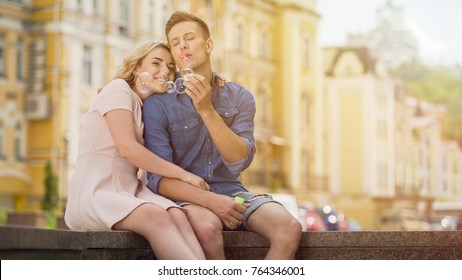 Carefree young man blowing soap bubbles, couple enjoying summer date in city - Powered by Shutterstock