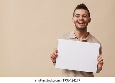 Carefree Young Man Holding Blank Sign in Studio