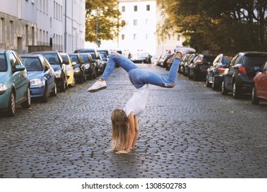 Carefree Young Woman Doing Spontaneous Handstand In The Middle Of City Street