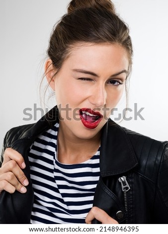 Careful boys I play rough. Portrait of a beautiful young woman in a studio wearing a leather jacket winking.