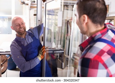 Careful couple of workmen inspecting windows at workshop
