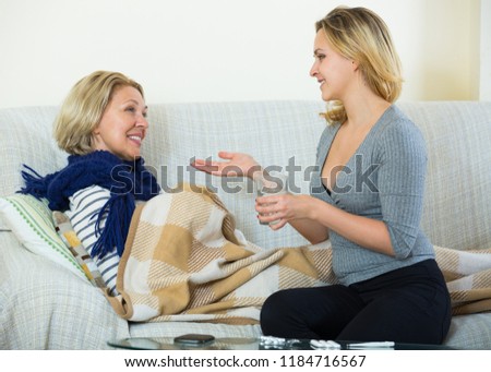 Careful daughter giving medication to senior mother with flue