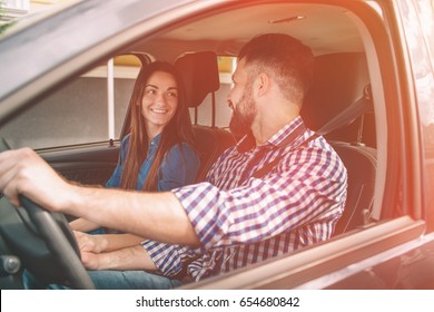 Careful driving. Beautiful young couple sitting on the front passenger seats and smiling while handsome man driving a car - Shutterstock ID 654680842
