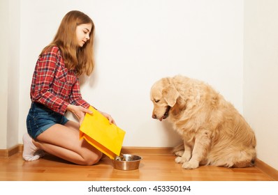 Careful girl filling pet's bowl with dry forage - Powered by Shutterstock