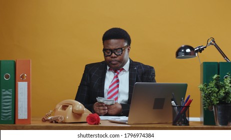 Careful Scared Black Head Businessman Counting His Money On Payday Hides Under Table Of Much Jealousy. Greedy Boss. Office Company. Comical Scene. Fun. Copy Space.