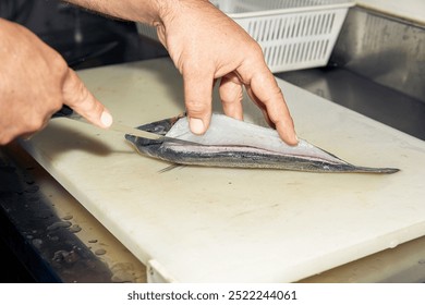 Carefully filleting fresh fish with hands on cutting board in a professional kitchen, fish preparation concept - Powered by Shutterstock