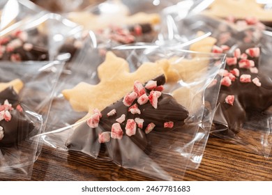 Carefully packaging Christmas cutout cookies, half-dipped in chocolate and presented in clear cellophane wrapping, perfect for festive gifting.