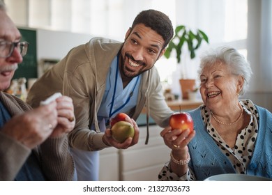 Caregiver Bringing Healthy Snack To Senior Woman And Man In Nursing Home Care Center.