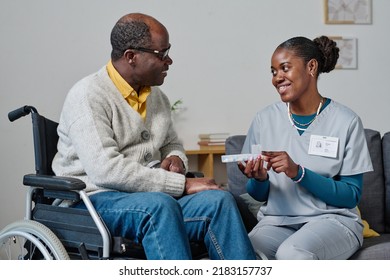 Caregiver giving pills to man with disability - Powered by Shutterstock