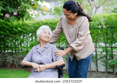 Caregiver help Asian elderly woman disability patient sitting on wheelchair in park, medical concept. - Powered by Shutterstock