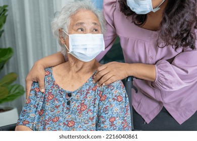 Caregiver Help Asian Senior Or Elderly Old Lady Woman Sitting On Wheelchair And Wearing A Face Mask For Protect Safety Infection Covid 19 Coronavirus.