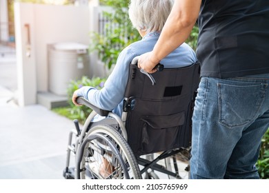 Caregiver help and care Asian senior or elderly old lady woman patient sitting on wheelchair at nursing hospital ward, healthy strong medical concept
