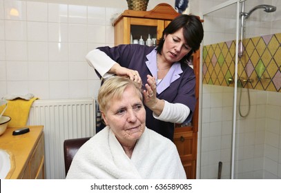 A caregiver helps an elderly woman with her hair - Powered by Shutterstock