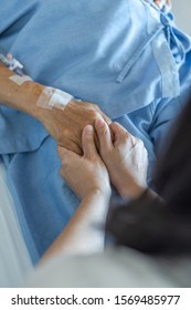 Caregiver Holding Elderly Senior Patient (ageing Old Adult Person) Hand In Hospital Bed Or Nursing Hospice, Geriatrician Palliative Home, While Caretaker Having  Medical Health Care Service