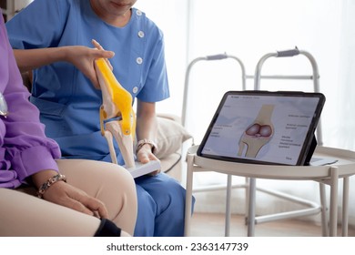 Caregiver or nurse helping check tendon and arthritis of knee or leg for diagnostic and rehabilitation while explaining senior woman with tablet living room at home, caretaker or physiotherapist. - Powered by Shutterstock