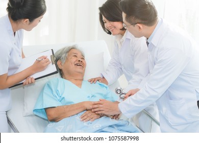 Caregiver And Nursing Home Concept. Asian Doctor And Nurse In Caregiver Team Checking Up Elderly / Senior Patient In Nursing Home.