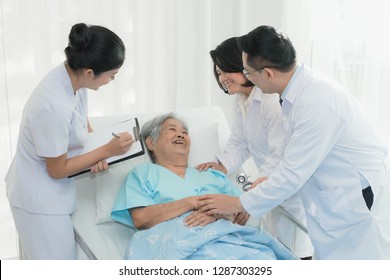 Caregiver And Nursing Home Concept. Asian Doctor And Nurse In Caregiver Team Checking Up Elderly / Senior Patient In Nursing Home.