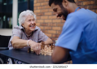 Caregiver playing chess and drinking coffe with his client outdoor at cafe. - Powered by Shutterstock