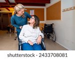 Caregiver pushing the wheelchair of a disabled woman in a day center for people with special needs