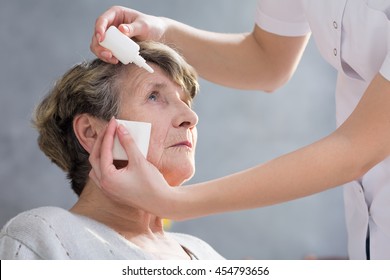 Caregiver Putting Eye Drops In Senior Woman's Eyes