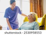 Caregiver in scrubs take care elderly woman at healthcare center. Medical healthcare caregiver assist elderly woman share warm happy moment. Happy elderly woman and healthcare staff assistant