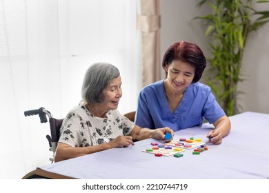 Caregiver And Senior Woman Playing Wooden Shape Puzzles Game For Dementia Prevention