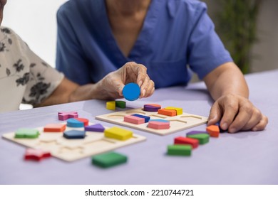 Caregiver And Senior Woman Playing Wooden Shape Puzzles Game For Dementia Prevention