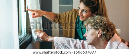 Caregiver looking through the window with elderly patient in wheelchair