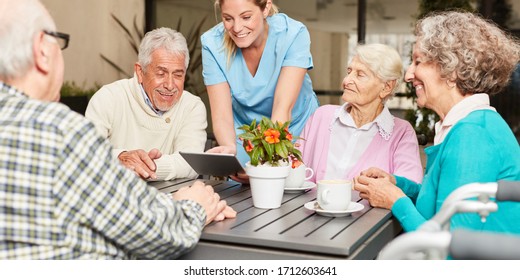 Caregiver with tablet pc and a group of seniors in retirement home