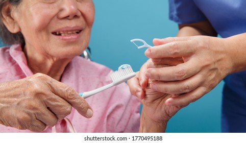 Caregiver Take Care Asian Elderly Woman While Using Dental Fross Stick.