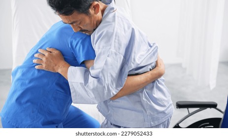 A caregiver transferring an elderly person from a nursing bed to a wheelchair. - Powered by Shutterstock