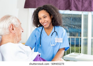 Caregiving Nurse Happy With Elder Patient In Hospital Bed.