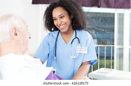 Caregiving Nurse Happy With Elder Patient In Hospital Bed.