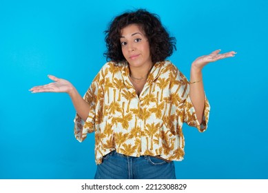 Careless Attractive Brunette Arab Woman Wearing Hawaiian Shirt Over Blue Background Shrugging Shoulders, Oops.