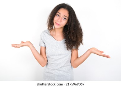 Careless Attractive Young Beautiful Brunette Teen Girl Wearing Grey T-shirt Over White Wall Shrugging Shoulders, Oops.