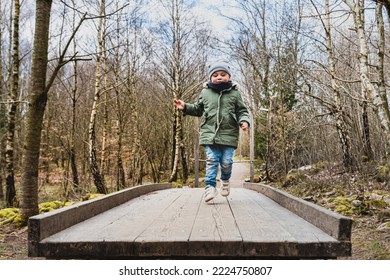 Careless child jumping or leaping on a wooden trampoline in the woods engaging in a funny outdoor activity. Lighthearted kid hopping on a timbered board or launching pad among bare trees in a forest - Shutterstock ID 2224750807