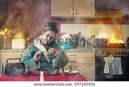 Careless girl talking on phone and makinger her nails while the kitchen is on fire.