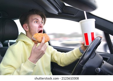 Careless Handsome frightened fearful guy driver young scared man screaming shocked about to have traffic accident driving car on road holding steering wheel of automobile eating burger drinking soda