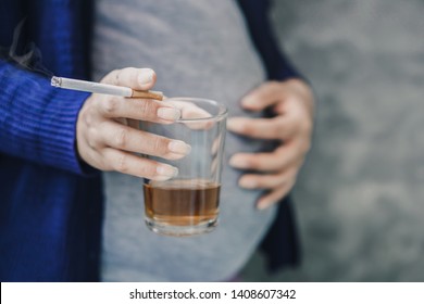 careless pregnant Asian woman hand drinking glass of alcohol and smoking cigarette 