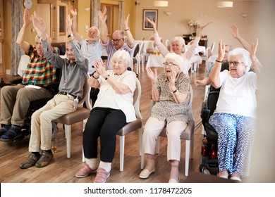 Carer Leading Group Of Seniors In Fitness Class In Retirement Home