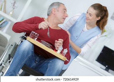 Carer Looking After Disabled Man At Meal Time