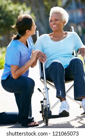 Carer Pushing Senior Woman In Wheelchair