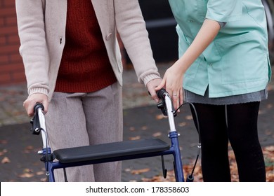 Carer teaching elder lady using a walker