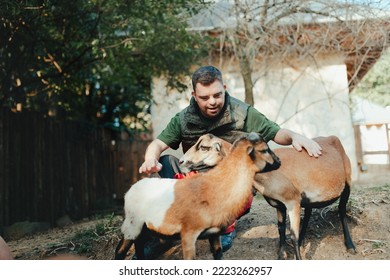Caretaker with down syndrome taking care of animals in zoo, stroking goats. Concept of integration people with disabilities into society.