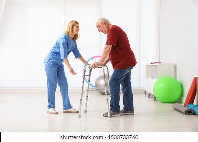 Caretaker Helping Elderly Man With Walking Frame Indoors