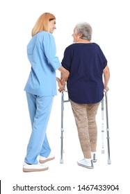 Caretaker Helping Elderly Woman With Walking Frame On White Background