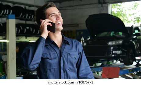 In A Caretaker A Mechanic Uses The Phone To Respond To Customer Messages And Calls As A Car Customer. Concept Of: Warranty, Security, Insurance And Assistance, Reviews, Technology And Customer Care.