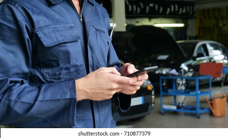 In a caretaker a mechanic uses the phone to respond to customer messages and calls as a car customer. Concept of: warranty, security, insurance and assistance, reviews, technology and customer care. - Powered by Shutterstock