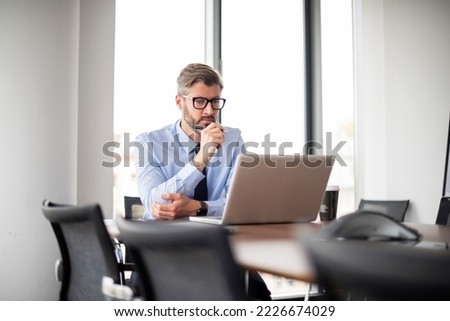 Care-worn middle aged businessman working at the office and using laptop. Professional man looking anxious.