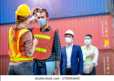 Cargo container or engineer worker use infrared thermometer measure temperature of other staff in shipping container workplace area and they stay in line during covid pandemic in around the factory.